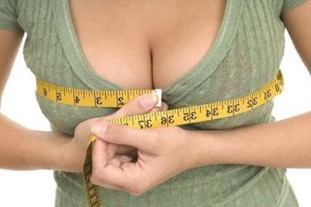 Женщина измеряет объем груди: после родов можно восстановить форму и объем груди