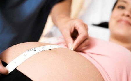 Врач измеряет живот беременной: небольшая отслойка плаценты на ранних сроках может компенсироваться за счет роста детского места