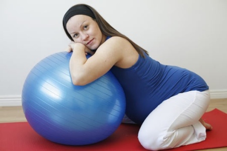 Беременная выполняет упражнения на фитболе 
