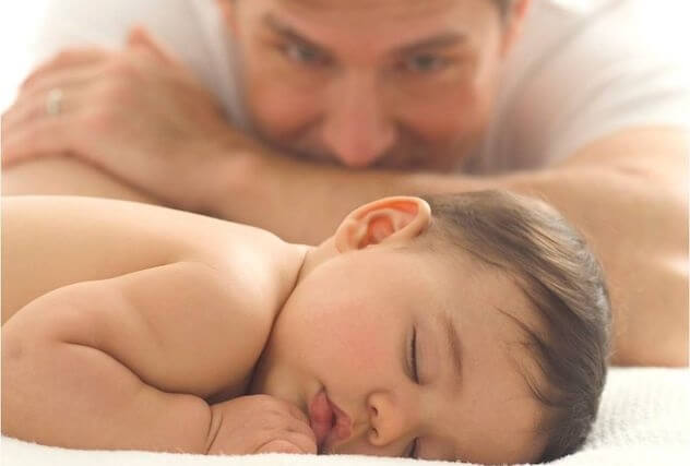 Мужчина смотрит на спящего ребенка