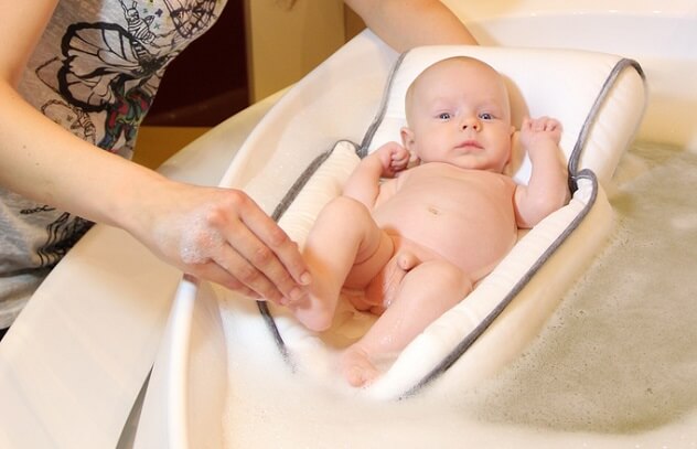 Новорожденный ребенок лежит в матрасике для купания