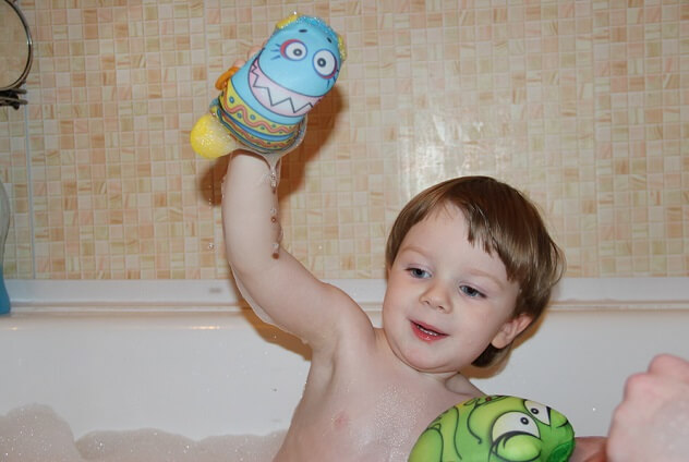 Мальчик играет игрушками в ванной