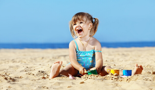 ребенок играет с песком на море