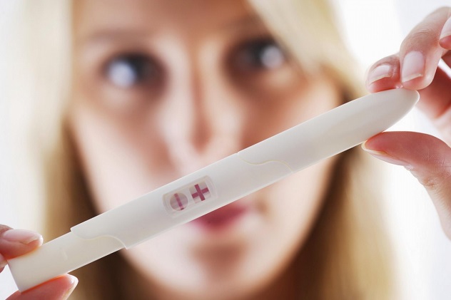 Женщина держит положительный тест на беременность