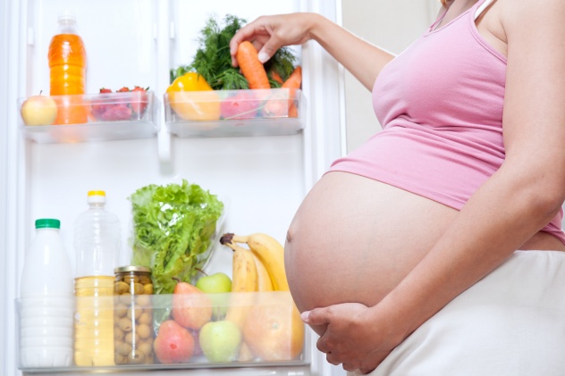 беременная достает овощи из холодильника
