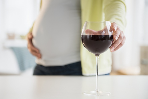 беременная берет бокал с вином