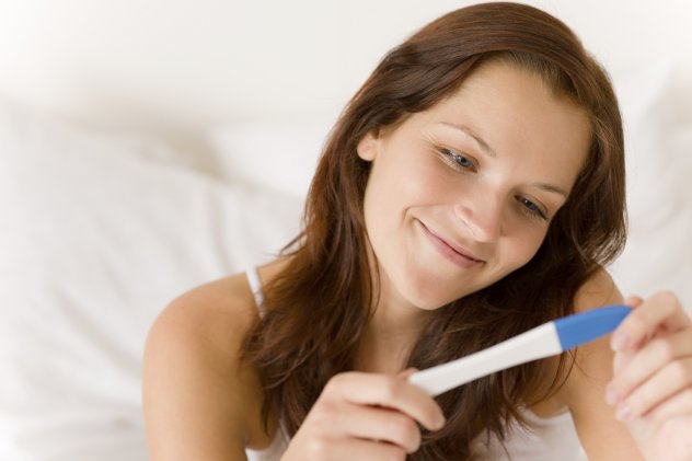 девушка держит тест на беременность