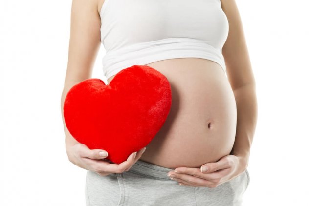 беременная держит плюшевое сердце