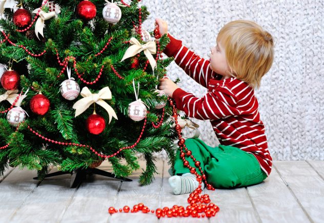 маленький ребенок украшает елку