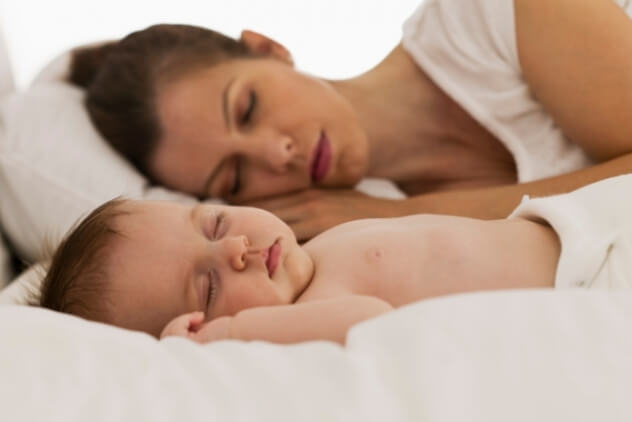 Маленький ребенок спит с мамой в кровати